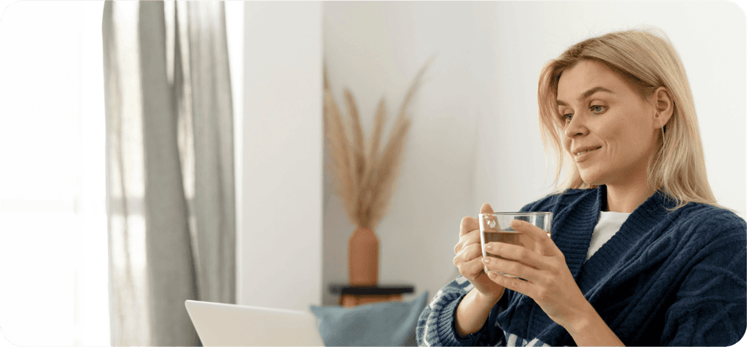 Žena sedící před notebookem s čajem v ruce.