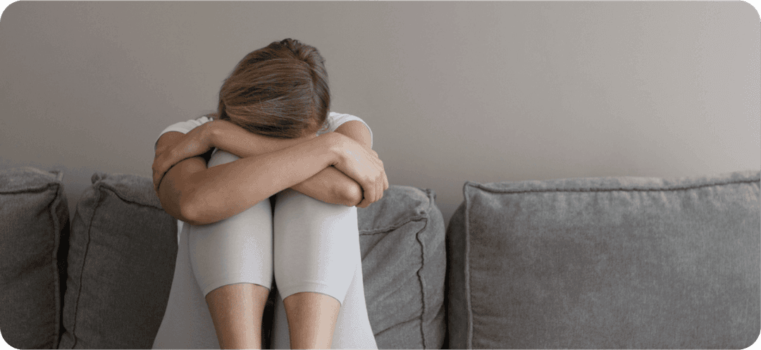 Depresivní žena sedící na gauči.