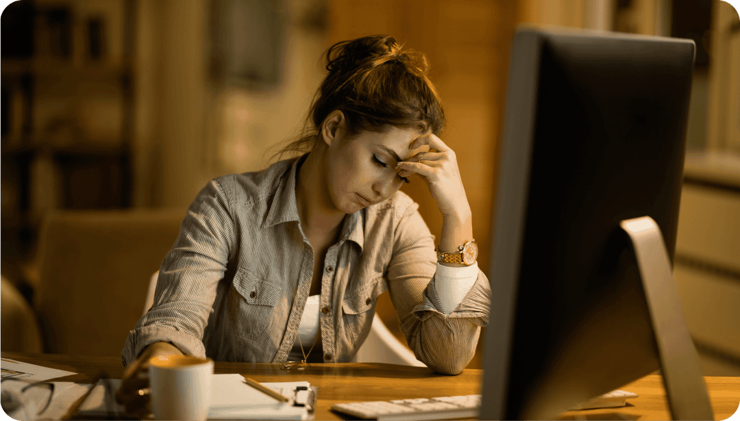 Unavená žena sedící za počítačem.